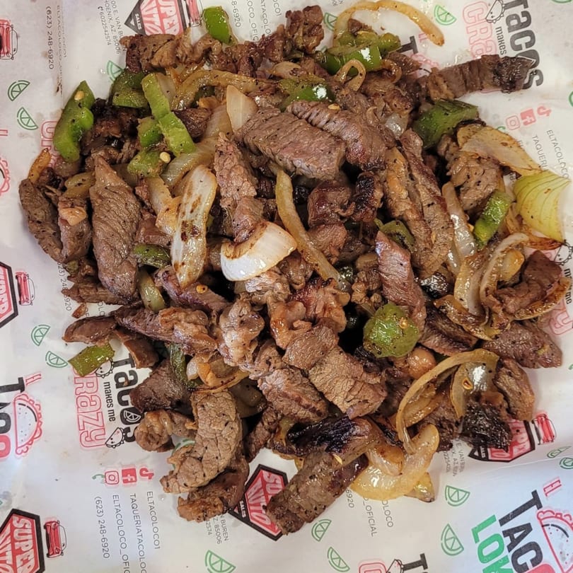 El Taco Loko's grilled steak fajita meat with onions and green bell peppers on branded paper.